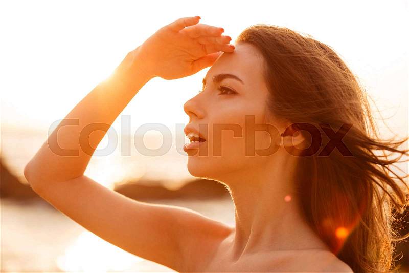 Close up picture in profile of attractive brunette woman looking away on sunset, stock photo