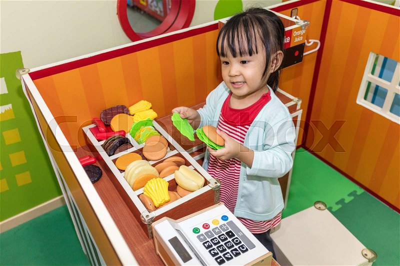 Asian Chinese little girl role-playing at burger store at indoor playground, stock photo