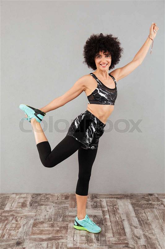Full length photo of smiling sports woman warming up and looking at the camera, stock photo