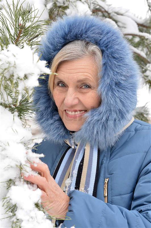 Mature woman in winter clothes posing outdoors, in good mood, stock photo