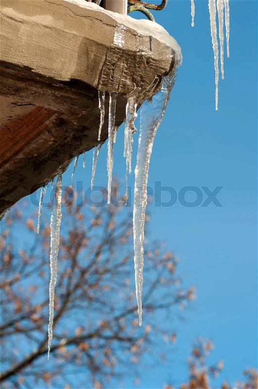 Icicles hang from the roof of the balcony in the street in winter, stock photo