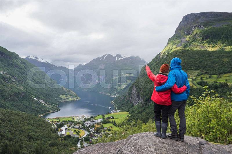 View of the tourist village Geiranger, Norway. Tourists stand at a panoramic point and look at Geirangerfjord and the mountains, stock photo