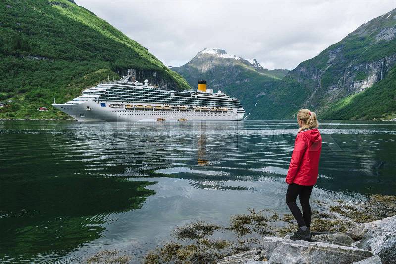 Cruise liner in the fjord. Girl on the shore of the Geirangerfjord near the town of Geiranger, Norway, stock photo