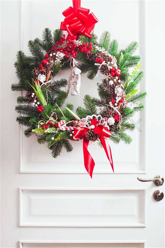 Christmas wreath hangs on the white doors. Red and white elements, bow for decorating holiday house, stock photo