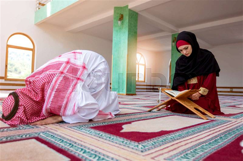 Muslim man and woman praying in mosque, stock photo