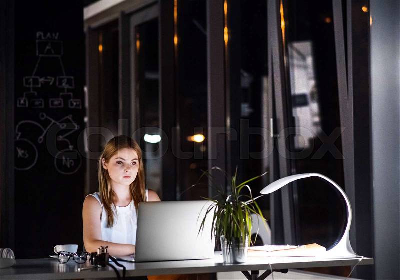 Beautiful young businesswoman in the office at night working late, stock photo