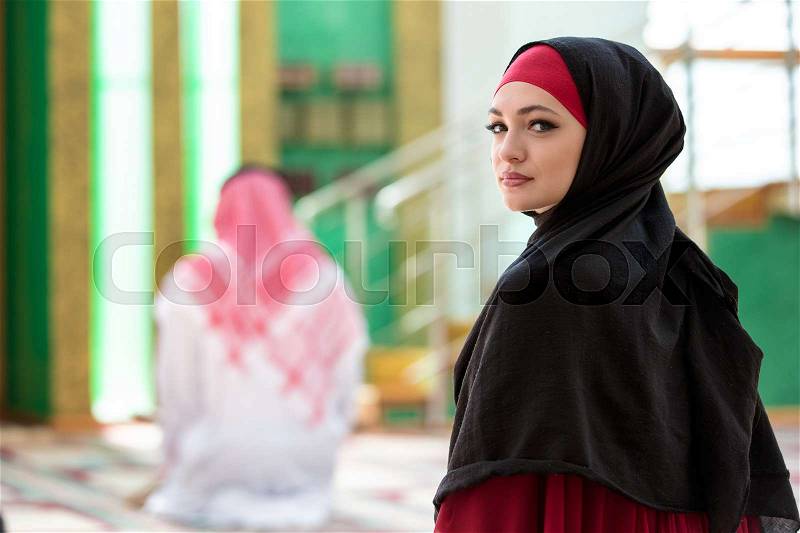 Muslim man and woman praying in mosque, stock photo