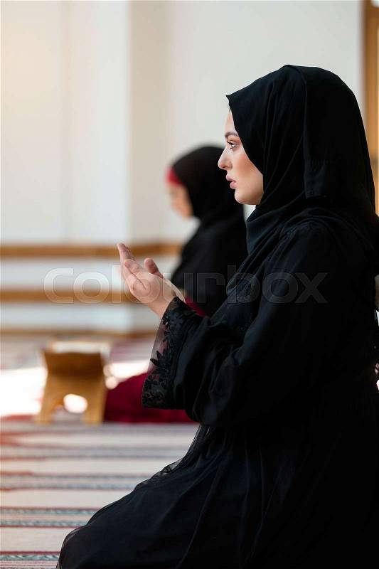 Two Muslim women praying inside beutiful mosque, stock photo