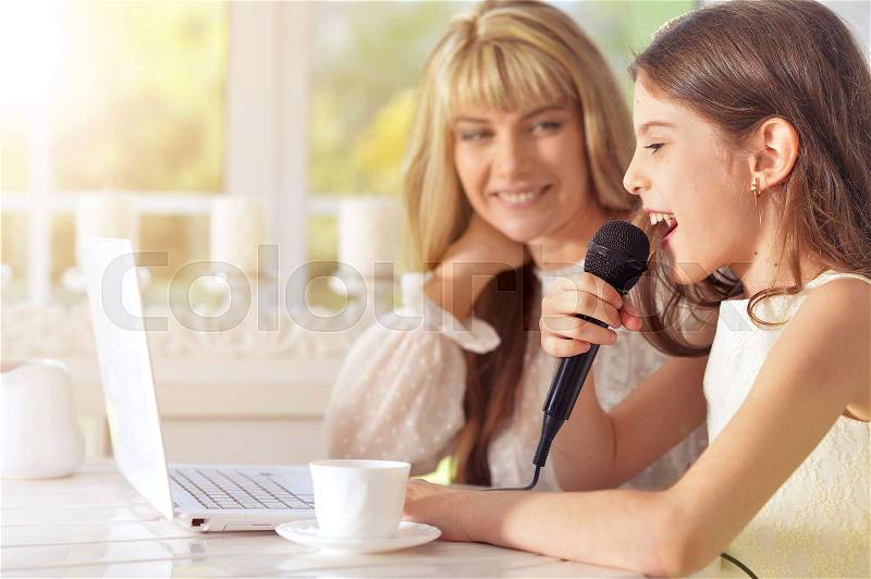 Portrait of a mother and daughter singing karaoke together, stock photo