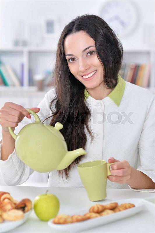 Close up portrait of beautiful young woman pouring tea, stock photo