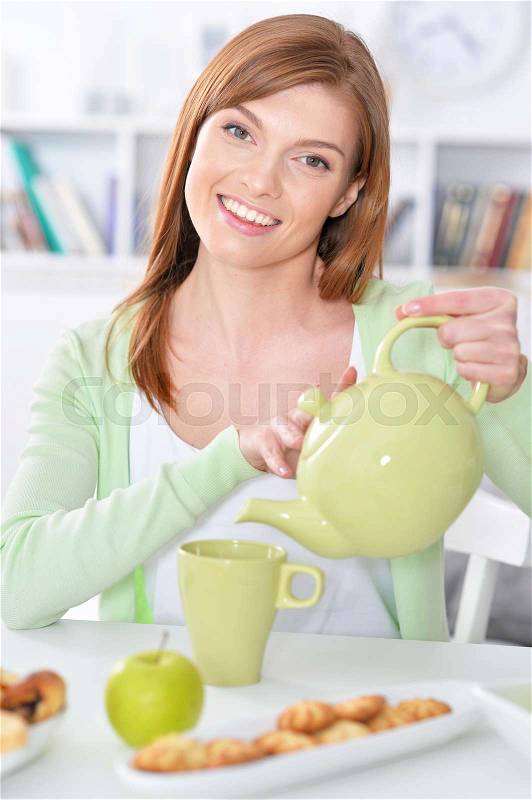 Close up portrait of beautiful young woman pouring tea, stock photo