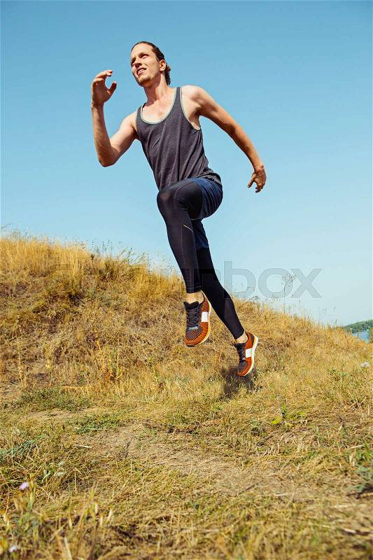 Running sport. Man runner sprinting outdoor in scenic nature. Fit muscular male athlete training trail running for marathon run. Sporty fit athletic man working out in compression clothing in sprint, stock photo