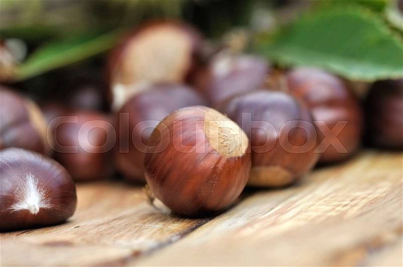 Close on sweet chestnuts on a wooden background , stock photo