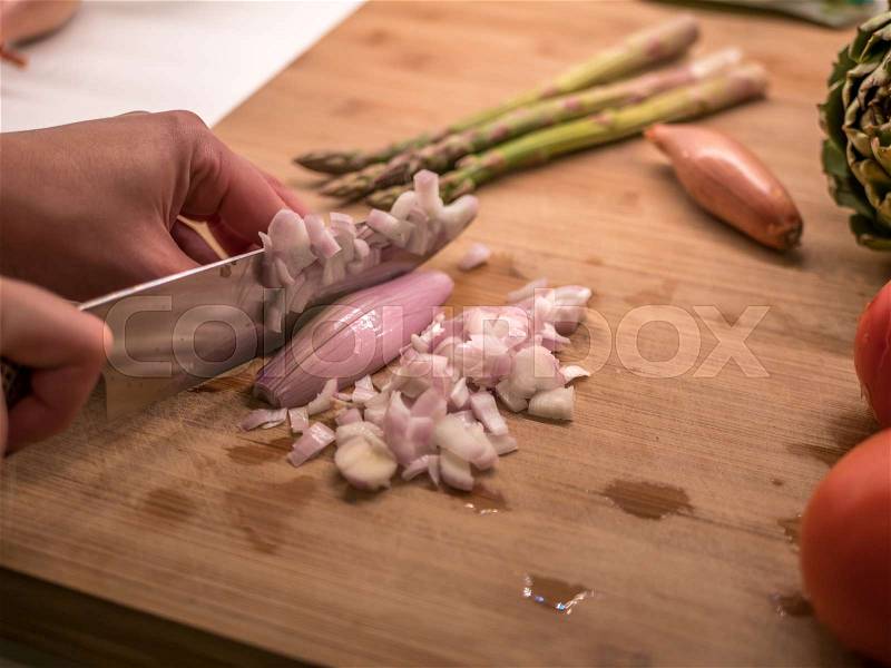 Chopping shallot onion on a wood cutting board, stock photo