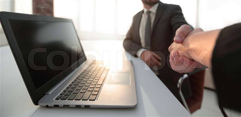 Business partners handshaking over business objects on workplace, stock photo