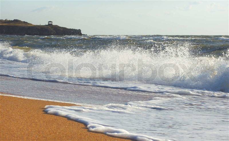 Sea surf great wave break on coastline and cape with pavilion at a distance, stock photo