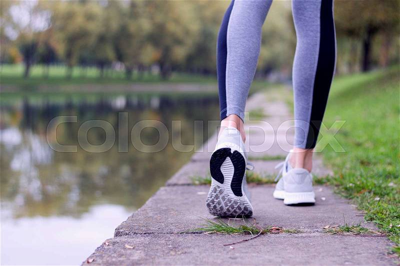 Sporty woman running on the river bank. Fitness and workout wellness concept, stock photo
