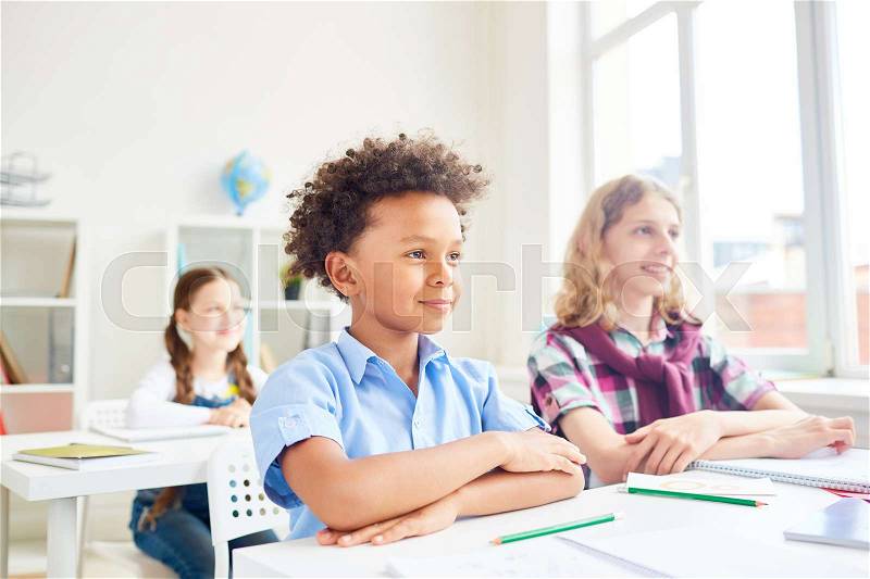 Happy school audience sitting by desk and listening to teacher, stock photo