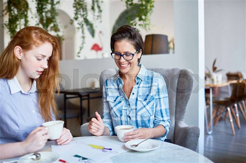 Two fashion-designers discussing sketches of new models of clothing, stock photo