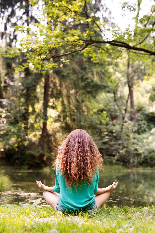 Unrecognizable girl practices yoga in the morning forest. Young woman sits,relaxes and meditates in nature, stock photo