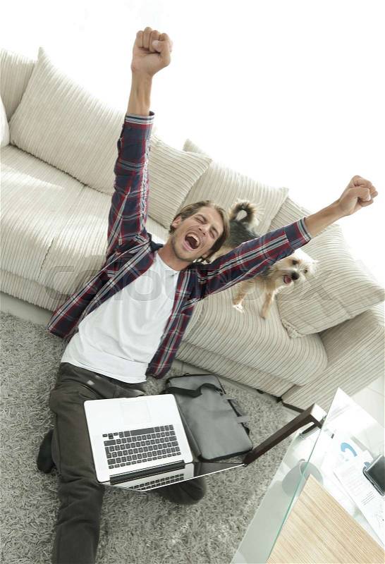 Happy guy with laptop jubilant in spacious living room. concept of success, stock photo