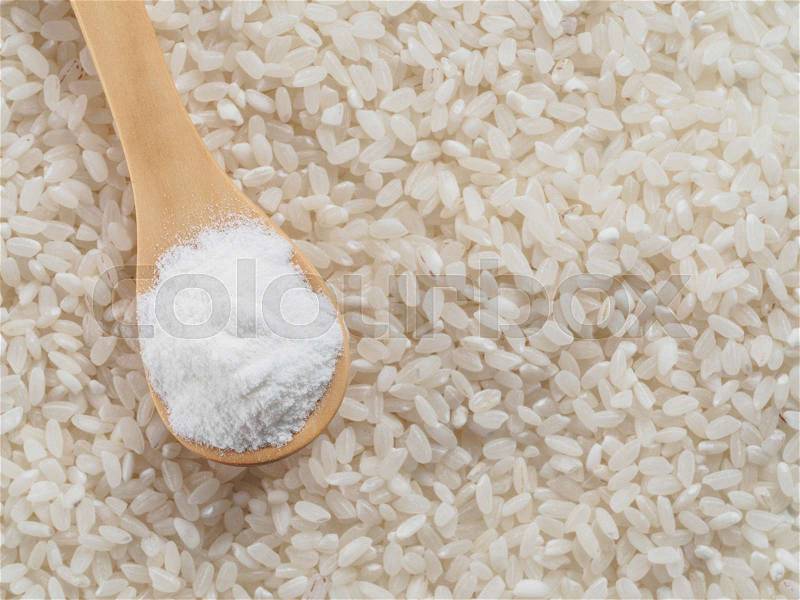 Rice flour in wooden spoon and rice grains. whole-grain rice flour on rice grains background. Copy space. Top view or flat lay, stock photo