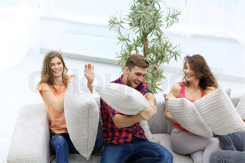 Group of friends playing pillow fight, sitting on the couch.photo with copy space, stock photo