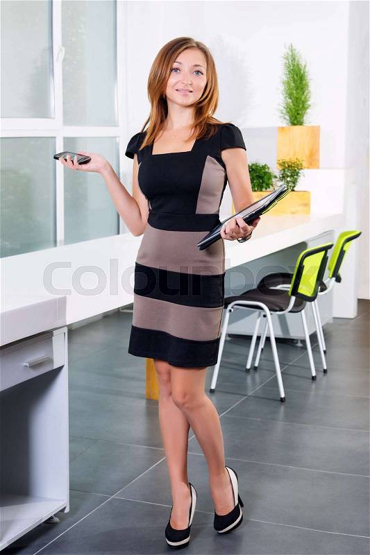 Young businesswoman in modern bright office holding the tablet and smartphone with a list of tasks. Free space for text. Business concept of office work, stock photo