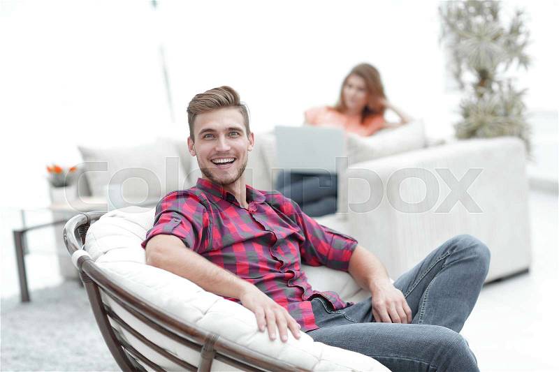 Happy young man sitting in a big chair on blurred background.photo with copy space, stock photo