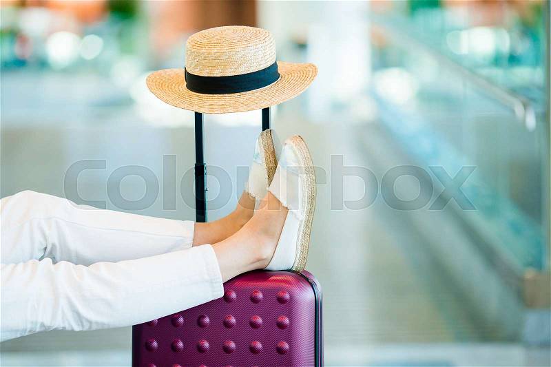 Young woman in an airport lounge waiting for landing. Closeup legs on the baggage, stock photo