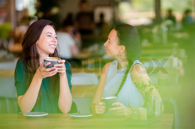Happy smiling young women with coffee cups at cafe. Communication and friendship concept, stock photo
