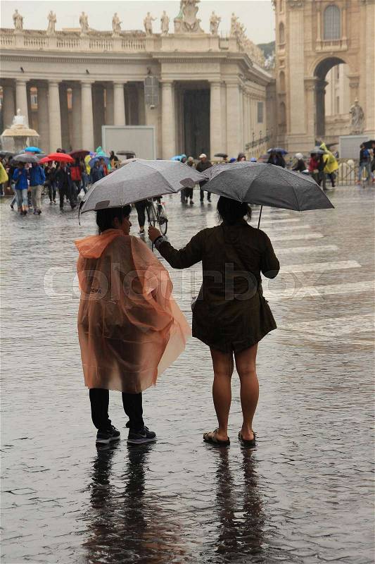 Two ladies under the grey umbrellas in the rain at St. Peter's Square in Rome in Italy in the wet summer, stock photo