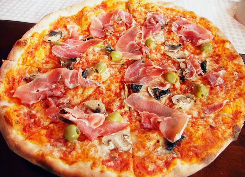Italian pizza with italian ham, olives and field agaric, stock photo