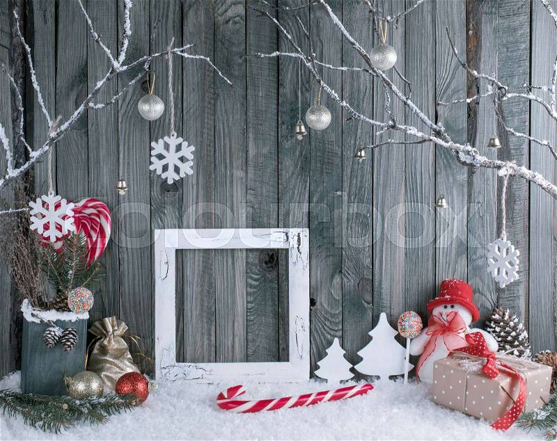 Christmas interior with snowman, photo frame, decorative branches, presents and candy canes on wooden planks background. New Year winter composition. , stock photo