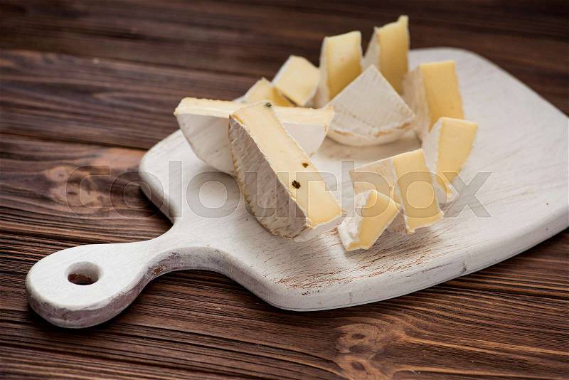 Pieces of cheese brie set on white wooden board. milk product background, stock photo