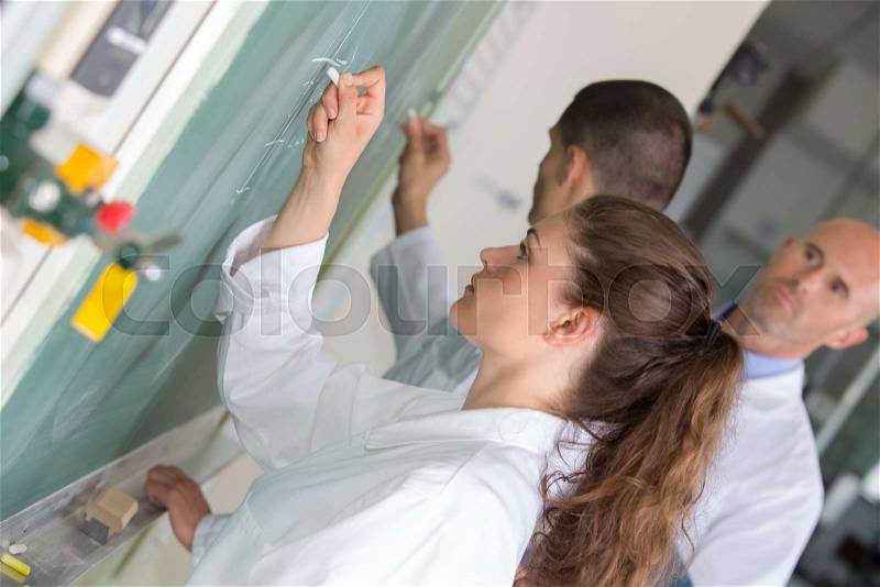Female student write chemical formula in the classroom, stock photo