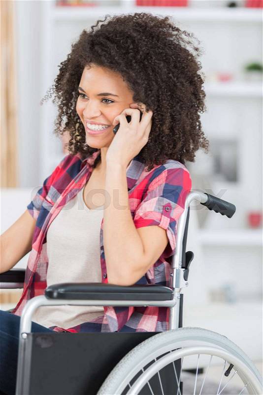 Disabled woman on wheelchair using a mobil phone, stock photo