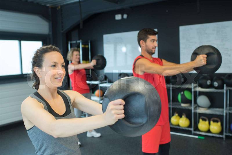 People in the gym holding weight ball, stock photo