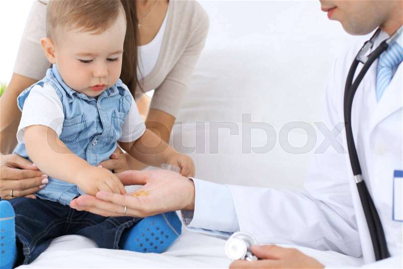 Little boy child with his mother at health exam at doctor\'s office. Patient takes pills from physician\'s hand, stock photo