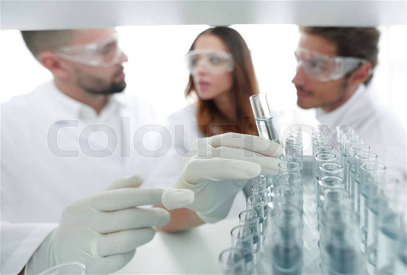 Background image is a group of scientists studying the liquid in the glass tube. the concept of the research, stock photo