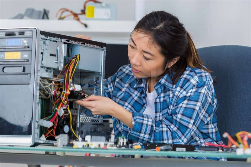Female pc technician soldering a chip from a desktop computer, stock photo