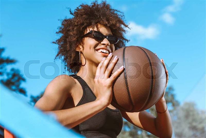Young african-american woman in sports bra throwing a basketball ball, stock photo