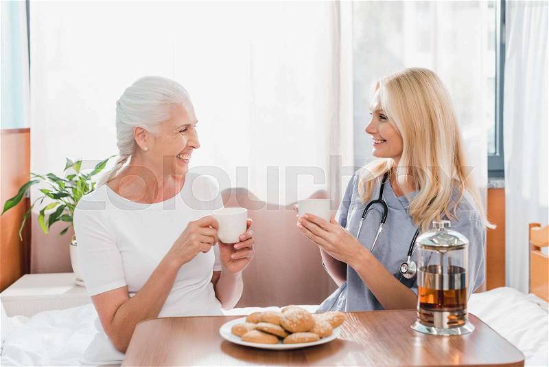Nurse and patient drinking tea and smiling each other in hospital, stock photo