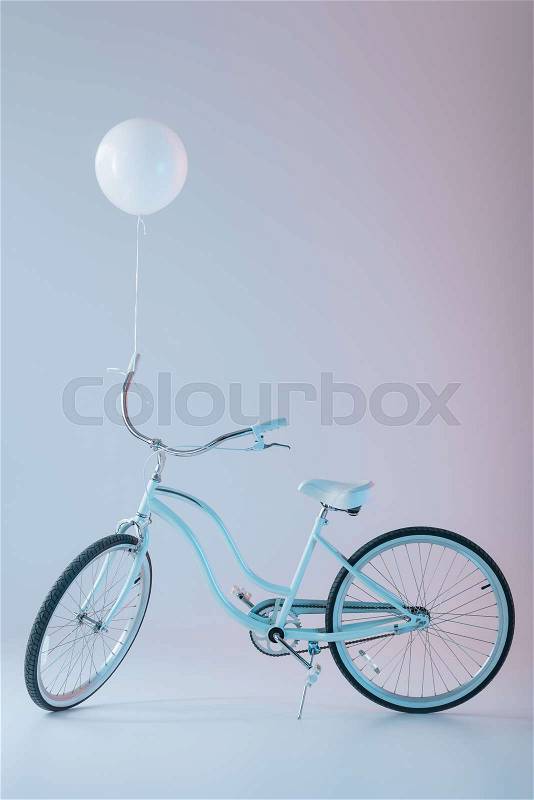 Stylish bicycle with white balloon, isolated on purple, stock photo