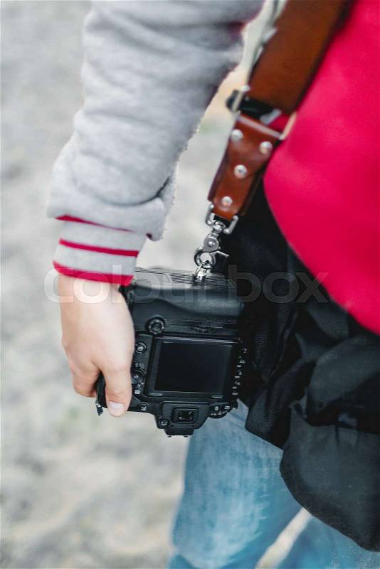 Photo camera on a leather strap. Photographer holds a camera in the hand. Close-up. A, stock photo
