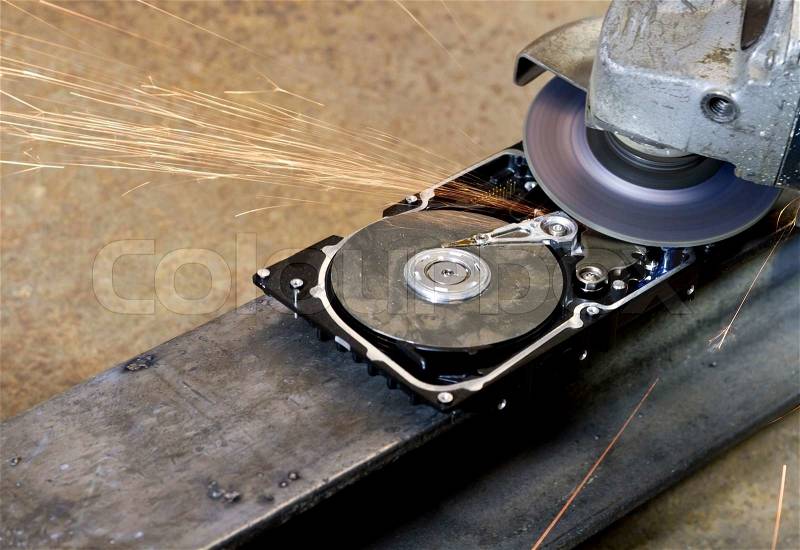 Hard disk drive with rotating grinder and sparks in front of rusty back, stock photo