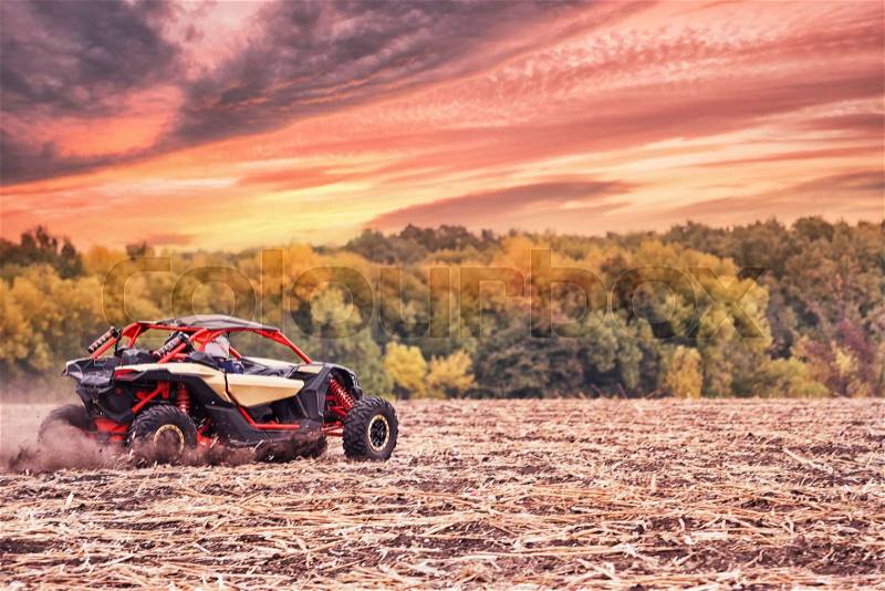 Racing quad bike in a field under a dramatic sunset sky. The concept of speed and freedom, stock photo