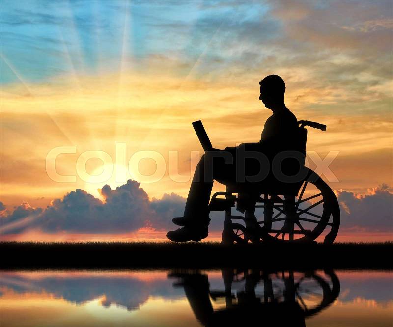 A disabled person in a wheelchair working with a laptop in hand near the river with his reflection. The concept of the opportunity to work for people with disabilities, stock photo