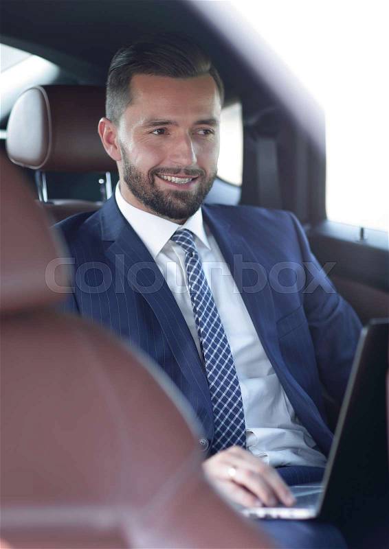 Portrait of a successful business man in the back seat of a car, stock photo