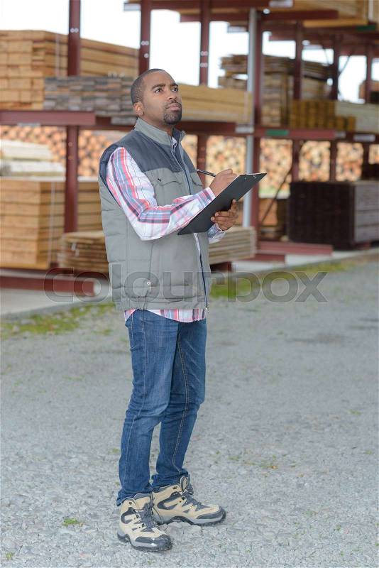 Man with clipboard in woodyard, stock photo